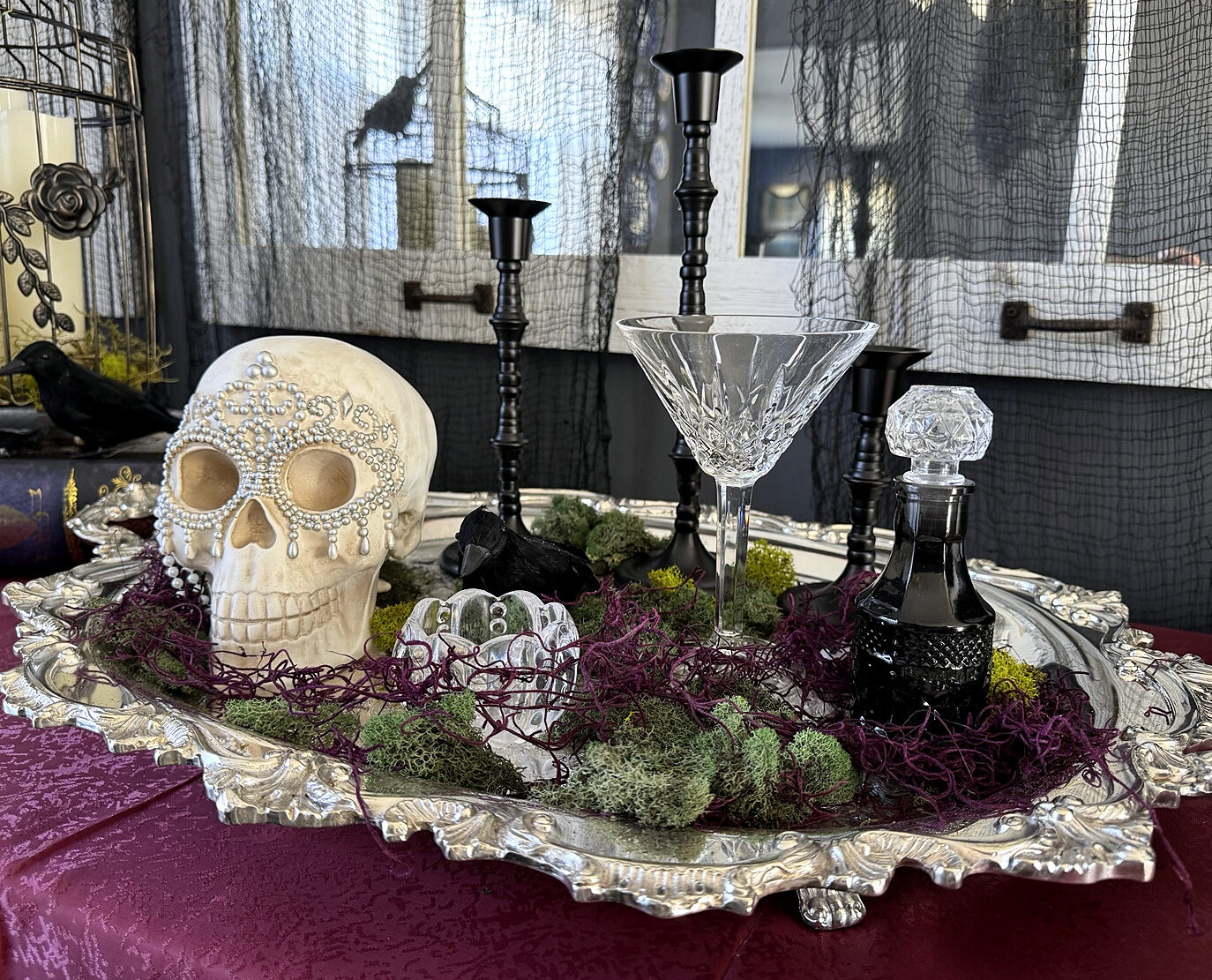 Victorian Gothic party vignette with skull, crystal coupe, black candlesticks, and silver tray