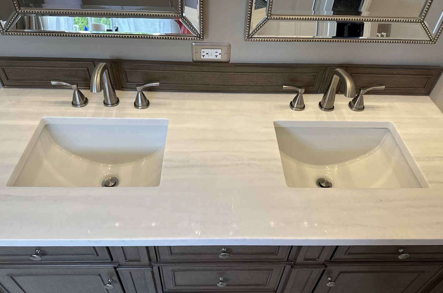 Silestone Arctic Fall double vanity top with soft gray and warm taupe striations, paired with white sinks, stainless faucets, and whitewashed walnut cabinetry.