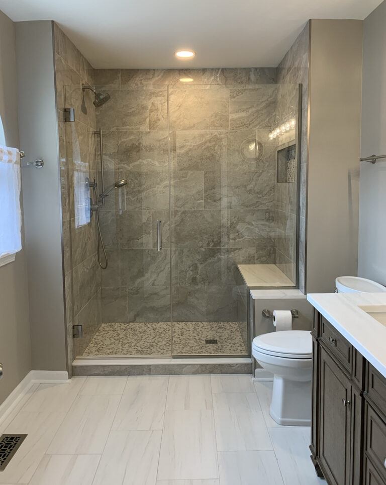 Finished master bathroom with a large frameless glass shower, light tile floors, and a walnut vanity.