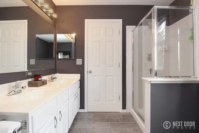 Original bathroom layout showing the white double vanity and small enclosed shower before the renovation.
